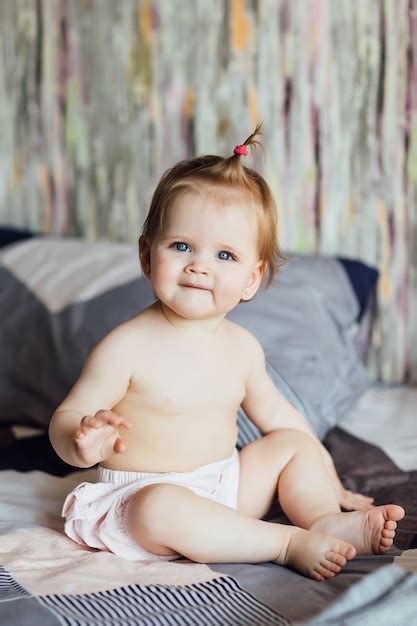 Petite Fille Mignonne Est Assise Sur Le Lit Avec Une Belle Coiffure