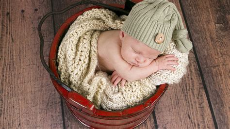 Child Baby Is Sleeping Inside Wood Basket Wearing Green Woolen Knitted