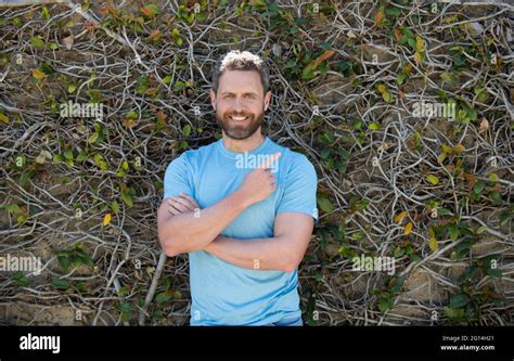 Happy Bearded Mature Man In Summer Shirt Pointing Finger On Natural Background Advertisement