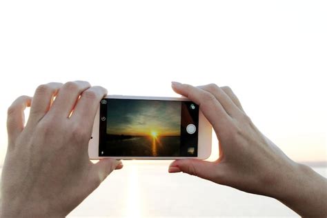 Manos femeninas sosteniendo un teléfono inteligente y tomando fotos de