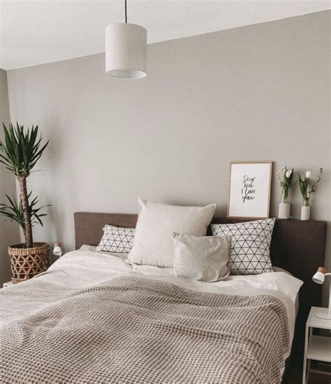 A Bed Sitting In A Bedroom Next To A Potted Plant On Top Of A Table