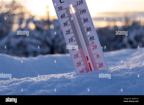 Thermometer On Snow Shows Low Temperatures In Celsius Or Farenheit On