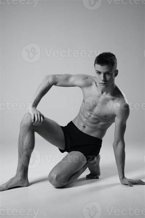 Athlete Sitting On The Floor Indoors In Shorts And Naked Torso Black And White Photo Of