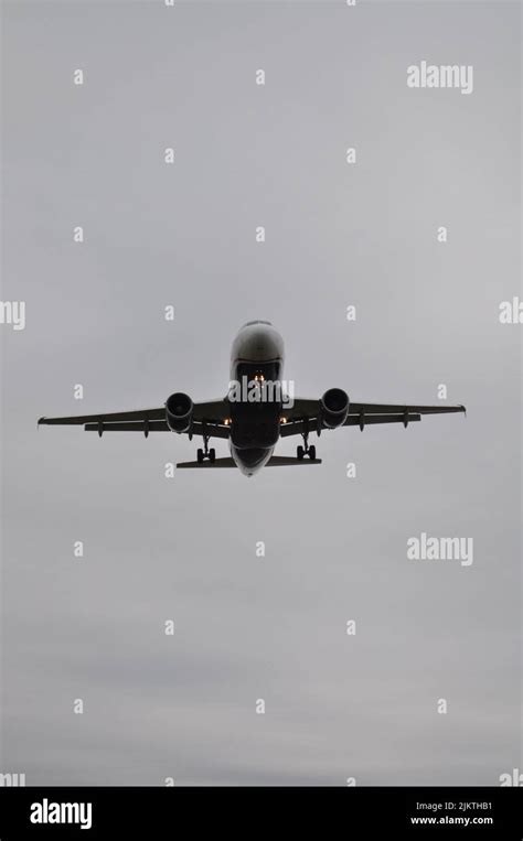 A Vertical Low Angle Grayscale Shot Of A Plane Flying In The Sky Stock