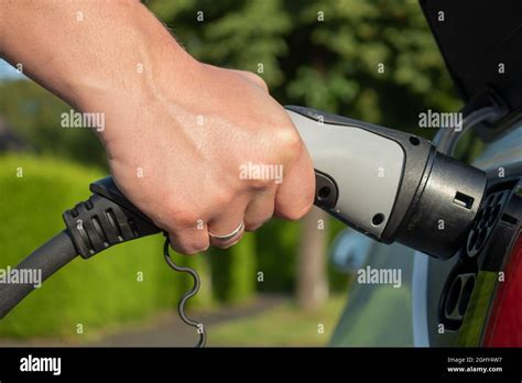 Eletric Car Charging In Summer Closeup Photo With Male Hand Green