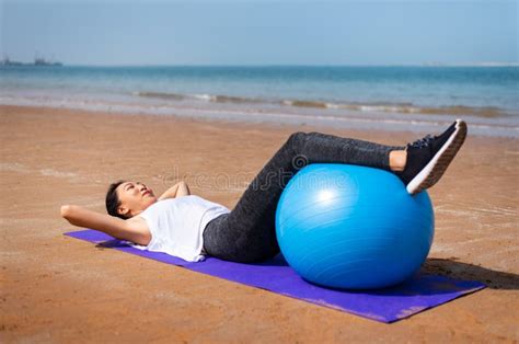 Mulher Que Exercita A Bola Dos Pilates Na Praia Imagem De Stock