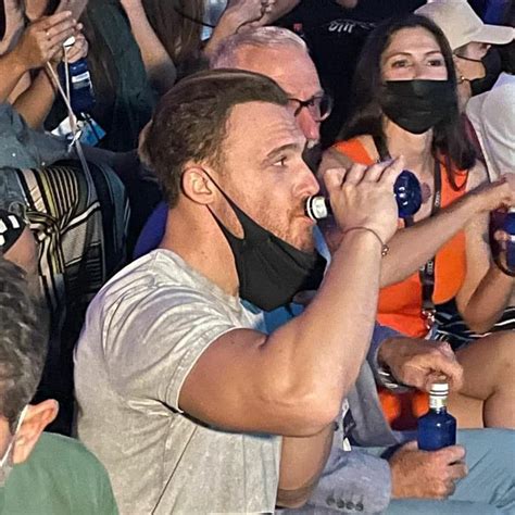 A Man Wearing A Face Mask While Sitting In Front Of A Group Of People