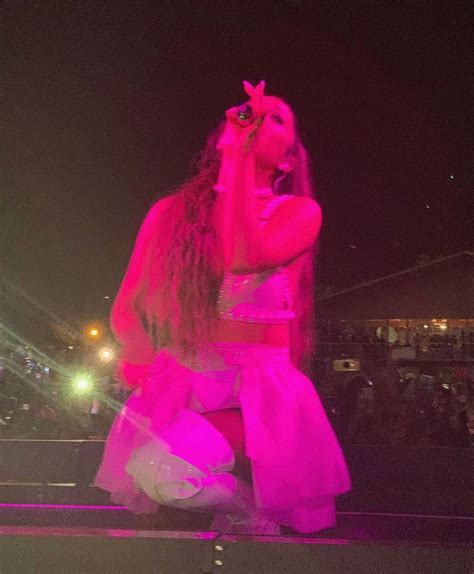 A Woman With Long Hair Wearing A Pink Dress And Holding A Cell Phone Up