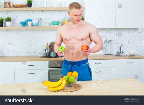 Стоковая фотография 1204540897 Muscular Man Naked Torso Kitchen Fruit