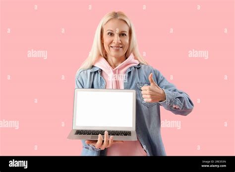 Mature Female Programmer With Laptop Showing Thumb Up On Pink