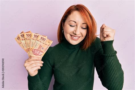 Beautiful Redhead Woman Holding 100 Mexican Pesos Banknotes Screaming