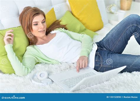 Portrait Of Young Beautiful Woman Relaxing In Bed At Home Using Laptop