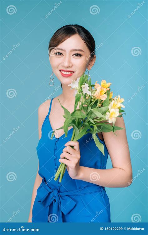 Attractive Asian Woman In Blue Dress Holding Bouquet Of Flowers Over