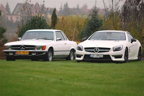 Two White Mercedes Benzs Parked Next To Each Other In The Grass Near