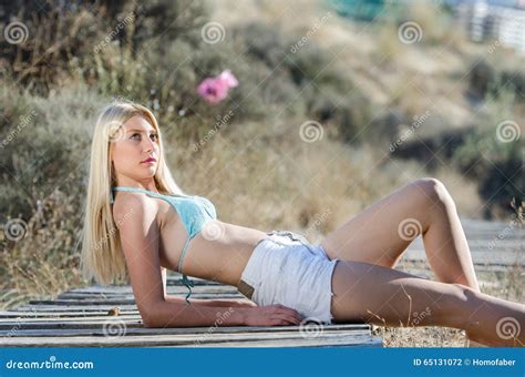 Beautiful Blonde Woman Lying In Front Of The Beach Entrance Stock Photo