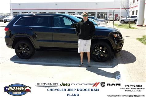 A Man Standing Next To A Black Jeep Parked In Front Of A Dealership