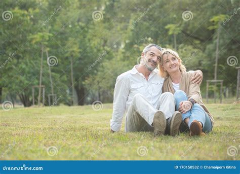 Senior Elder Caucasian Couple Sitting On Ground Together In Park In Autumn Wife Resting Head On