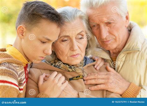 Close Up Portrait Of Sad Grandfather Grandmother And Grandson Hugging