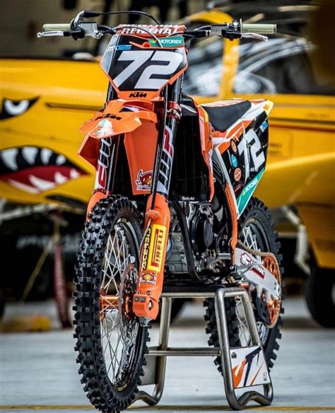 An Orange Dirt Bike Parked Next To A Yellow Boat