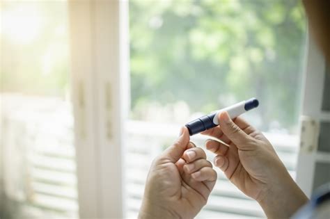 Gros plan des mains de la femme à l aide de la lancette sur le doigt