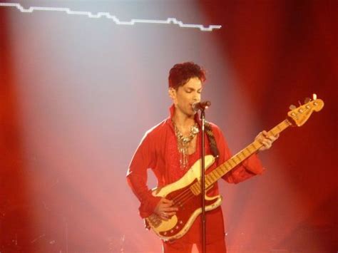 A Man Standing In Front Of A Microphone While Holding A Guitar