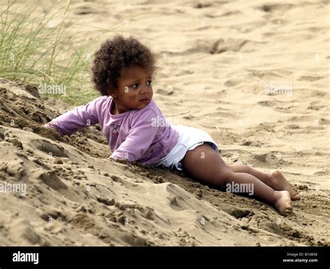 Little black baby girl playing in the sand, looking behind her Stock ...