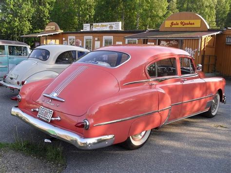 An Old Red Car Parked In Front Of A Building