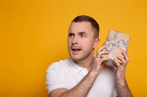 Premium Photo Thoughtful Man Holding Present On Yellow