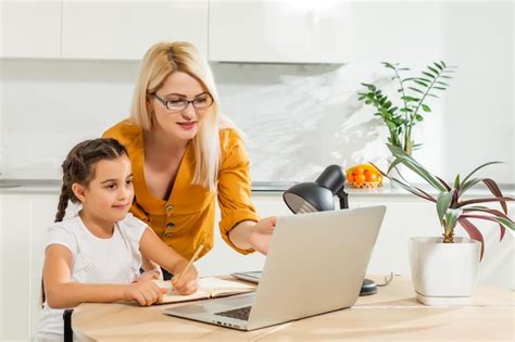 Belle Femme Aidant Sa Fille Faire Ses Devoirs Dans Une Cuisine