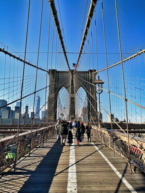 Premium Photo People Walking On Brooklyn Bridge Against Blue Sky