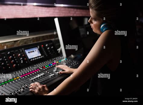 Female Audio Engineer Using Sound Mixer In Recording Studio Stock Photo