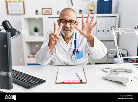 Mature Doctor Man At The Clinic Showing And Pointing Up With Fingers