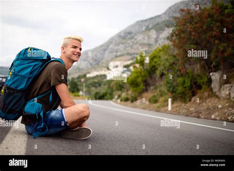 Travel Man Backpacking Hitchhiking On Road Trip Hitching A Ride From