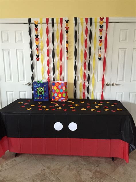 A Mickey Mouse Themed Birthday Party With Black And Red Table Cloths Streamers And Decorations