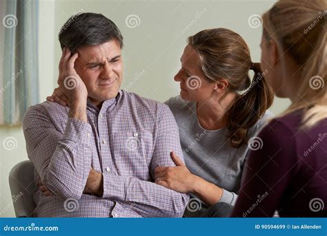 Mature Couple Talking With Counsellor As Woman Comforts Man Stock Image