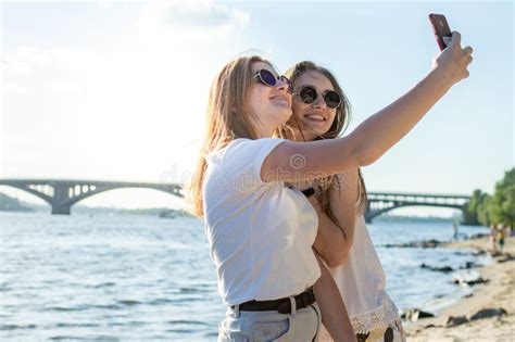 De Jeunes Filles Belles Sur La Plage Utilisant Un Smartphone Prennent