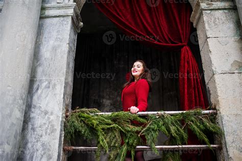 Brunette Plus Size Model At Red Against Arch With Curtains 10464089