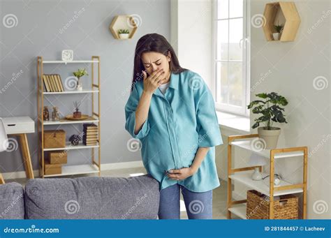 Young Pregnant Woman Suffering From Morning Sickness And Holding Hands