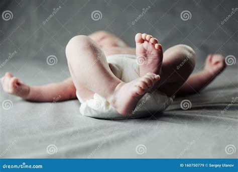 Newborn Baby Belly And Legs In Diaper Lying On White Bed Top View