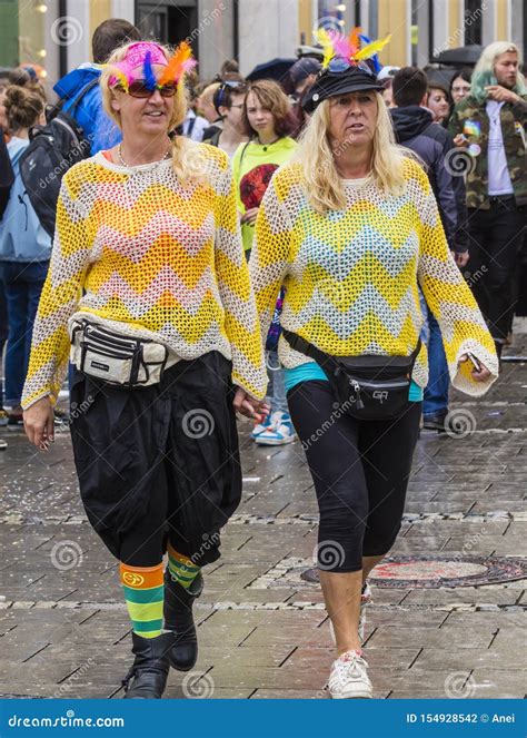 Two Women Holding Hands And Wearing Yellow Sweaters Attending The Gay Pride Parade Also Known As