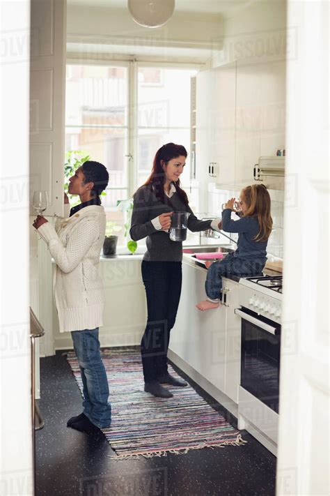Full Length Of Lesbian Couple With Girl In Kitchen Stock Photo Dissolve