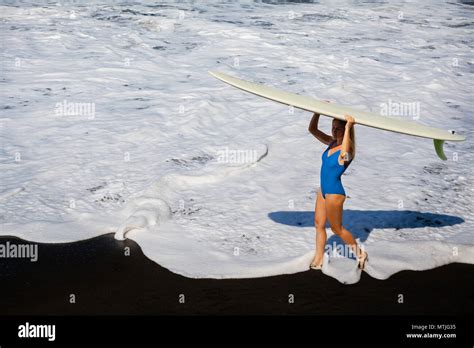 Sporty Girl In Bikini With Surf Board Walk On Black Sand Beach Young