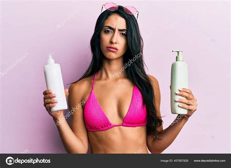 Beautiful Hispanic Woman Wearing Bikini Holding Sunscreen Lotion Clueless Confused Stock Photo