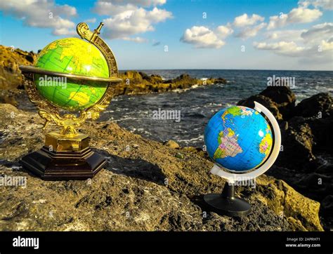 Shallow Focus Shot Of Two 3d Globe Model With A Blurred Ocean In The