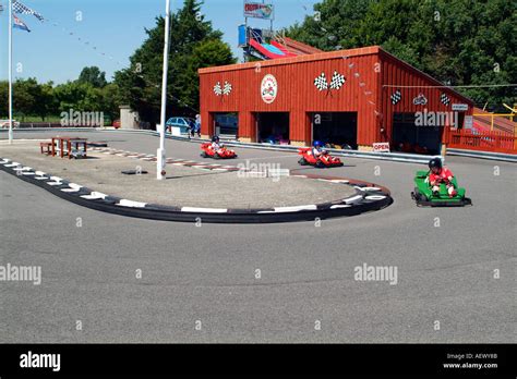 Children Having Fun Driving Go Karts Around A Track At An Amusement