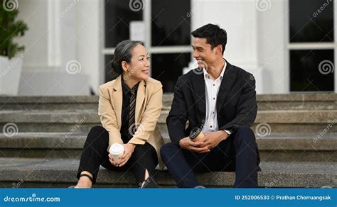 Shot Of Two Business People Sitting On Stairs Of Office Building And