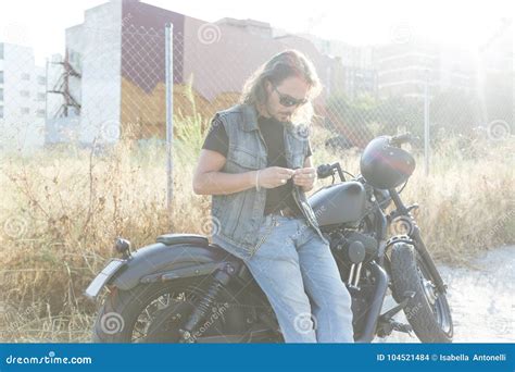 Type Aux Cheveux Longs De Brune Posant Sur Une Moto Faite Sur Commande