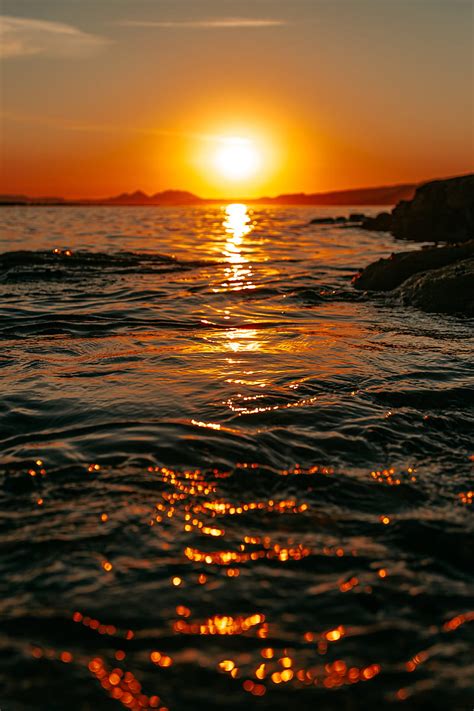 Sunset Sea Glare Rocks Sky HD Phone Wallpaper Peakpx