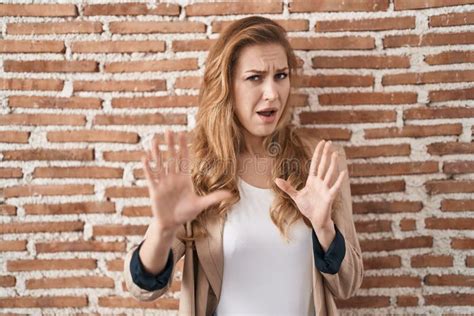 Beautiful Blonde Woman Standing Over Bricks Wall Afraid And Terrified With Fear Expression Stop