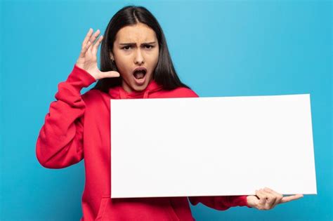 Joven latina gritando con las manos en alto sintiéndose furiosa frustrada estresada y molesta